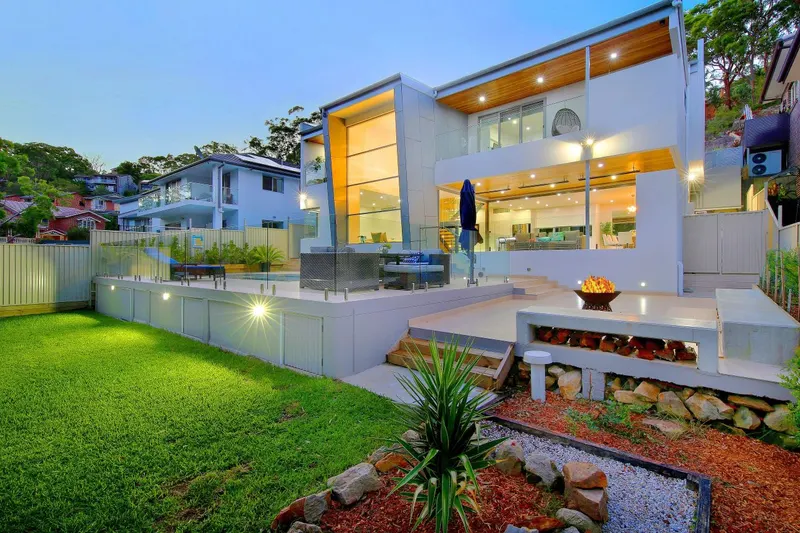 Architect-designed custom home in Illawong at twilight, with terraced garden and fire pit
