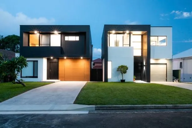 Detached dual occupancy homes in Kirrawee at dusk – black cladding and timber garage doors